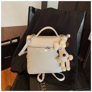Detail of off-white lychee pattern leather backpack with cute dog plush charm and strap