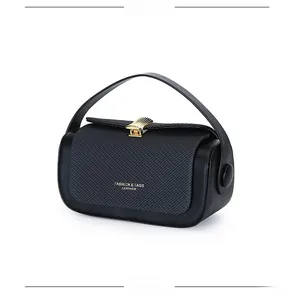 Detail of black leather box bag featuring woven texture and gold shell-shaped lock