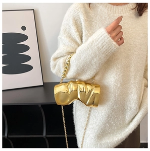 Détail d'un sac à main doré artistique avec texture ondulée et poignée en perles