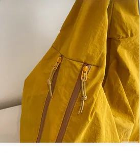 Detailopname van de soepele dubbele ritsen en nylon textuur op de gele shopper tas