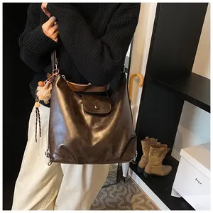 Detail of vintage brown leather hobo bag with tassel and pompom charm on model