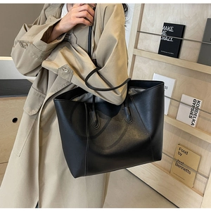 Détail d'un grand sac cabas en cuir noir avec de fines anses dans un cadre de vie moderne