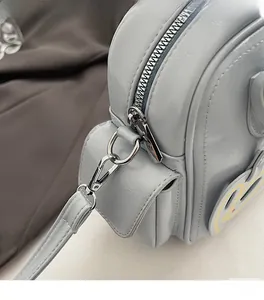 Close-up of silver metal hardware and zipper detail on light blue crossbody tote bag