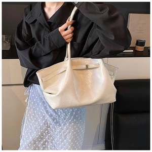 Detail of a creamy white large capacity tote bag with pleated design and metallic clasp