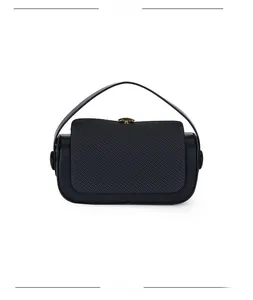 Detail of black top handle bag showing textured fabric flap and sleek leather body