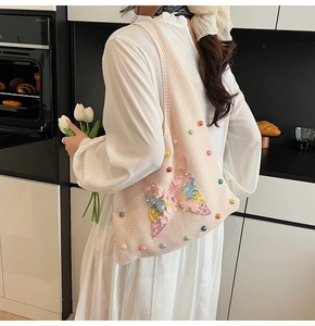 Détail du sac cabas en tricot rose avec grand papillon 3D et perles colorées
