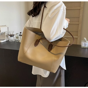 Vue détaillée d'un grand sac cabas kaki porté à l'épaule dans le décor d'un café moderne
