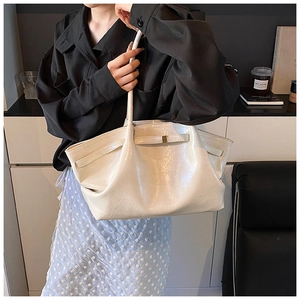 Detail of cream glossy patent leather tote bag with pleat design and gold buckle