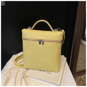 Detail of bright yellow leather square bag with litchi texture and silver double zippers