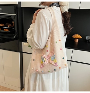 Détail du cabas en tricot rose avec applique papillon en dentelle 3D et perles colorées