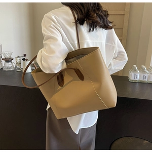 Grand sac cabas en cuir marron porté par un mannequin dans un café, montrant les détails