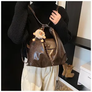 Detail of dark brown vintage PU leather backpack with a plush sheep pendant and straps