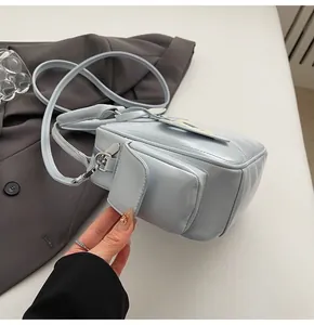 Detail of light blue patent leather tote bag showing front flap pocket on grey blazer