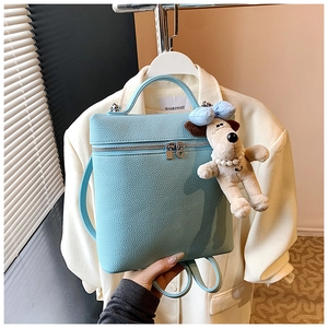 Detail of light blue pebble leather mini backpack with a cute dog plush charm accessory