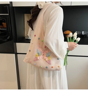 Détail du sac tricoté avec broderie papillon et accents de perles multicolores