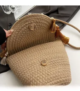 Detail of magnetic snap closure and woven texture on straw crossbody bag with tassels