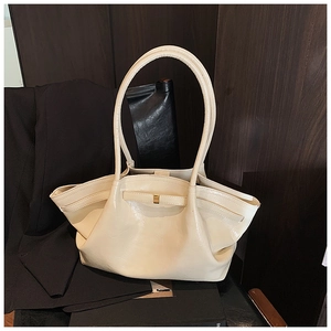 Detail of cream pleated tote bag with golden buckle and textured glossy finish