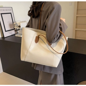 Mannequin portant un grand sac cabas crème avec lignes géométriques et anses brunes