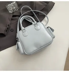 Light blue square Boston bag with silver hardware on gray suit and white background