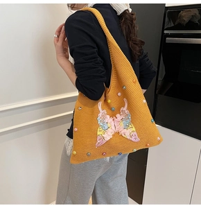 Détail du sac cabas en tricot jaune avec broderie papillon rose et perles nacrées