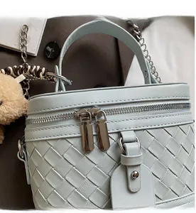 Detail einer hellblauen gewebten Handtasche mit Doppelreißverschluss und Plüschbär-Anhänger