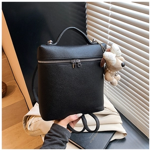 Detail of black pebbled leather backpack with silver zippers and pearl dog charm