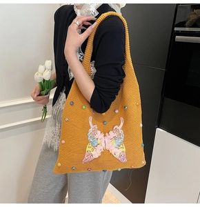 Détail du sac cabas en tricot jaune avec broderie papillon rose et perles nacrées