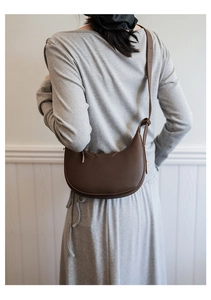 Detail einer braunen Halbmond-Tasche aus Leder mit feiner Litschimaserung und Gurt