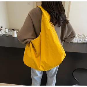 Lifestyle-opname van een ruime gele tote bag over de schouder in een modern café