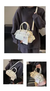 Detail view of a creamy white boston bag with multi-pockets and a cute bear card holder