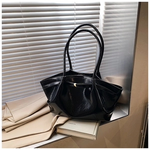 Macro shot of glossy black patent leather tote bag with elegant pleated texture and buckle