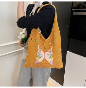 Détail du sac cabas en tricot jaune avec broderie papillon et ornements de perles