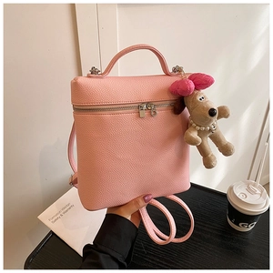 Detailed shot of pink pebble grain PU backpack with a cute puppy plush charm pendant