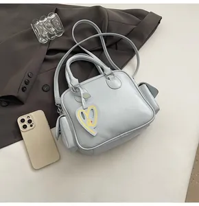 Detail of light blue Boston bag with dual handles and stylish heart smiley pendant