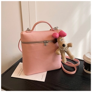 Detail of pink lychee leather handbag with a cute puppy plush charm and top handle