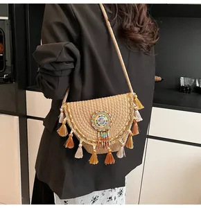 Detail of bohemian straw crossbody bag featuring cream tassels and colorful beaded ornament
