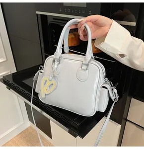 Close-up of light gray glossy tote bag with yellow heart charm on a black tray
