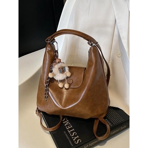 Brown leather versatile backpack for women with a cute sheep charm on an art book