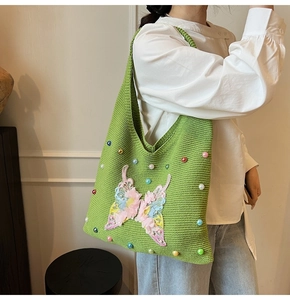 Détail du sac cabas tricoté vert avec broderie papillon 3D et ornements de perles