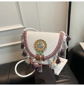 Detail of woven straw crossbody bag featuring handmade beadwork and colorful tassels