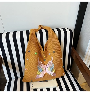 Détail d'un sac cabas en tricot jaune moutarde avec papillon 3D coloré et perles brodées