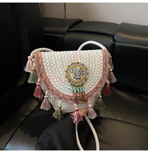 Detailed view of woven straw shoulder bag featuring colorful tassels and ethnic beadwork