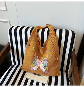 Détail d'un cabas en maille jaune avec écusson papillon complexe orné de perles