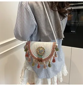 Detailed view of bohemian straw bag with colorful beadwork and long tassels on a model