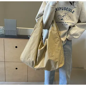 Grote kaki hobo-tas gedragen door een model in een informele lifestyle-omgeving