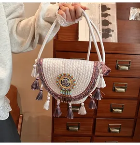 Detail view of a bohemian straw bag featuring colorful tassels and ethnic embroidery