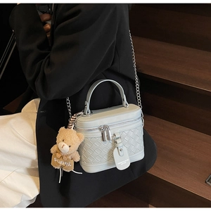 Detailansicht der hellblauen geflochtenen Ledertasche mit Kette und Teddybären-Anhänger