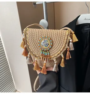 Detail of straw crossbody bag featuring beaded mandala pattern and colorful silky tassels