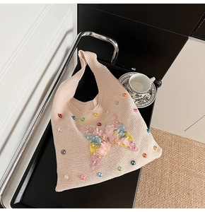 Détail d'un sac cabas en tricot rose avec broderie papillon et accents floraux colorés