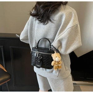 Detail der schwarzen gewebten quadratischen Tasche mit Metallkette und Plüschbär-Anhänger